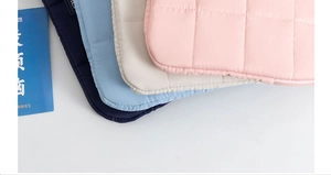 Close-up of quilted laptop sleeves in navy, blue, cream, and pink with soft textures