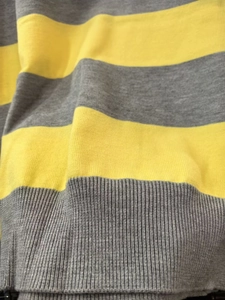 Detailed macro view of yellow and grey striped knit sweater with ribbed hem texture