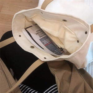 Detailed interior of a white canvas tote bag with brown straps and a zippered pocket