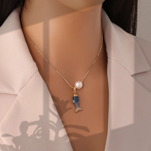 Gros plan d'un collier doré avec pendentif carpe koi bleue et perle blanche au cou