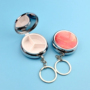 Detail of pink marble metal pill box keychain with mirror and three compartments