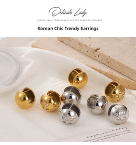 Detail of polished gold and silver hollow sphere stud earrings with heart pattern accents