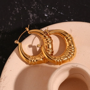 Detail of 18K gold-plated chunky hoop earrings with vintage wavy texture on ceramic