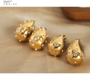Macro detail of gold teardrop earrings with embedded pearls and sparkling rhinestones