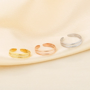 Detailed close-up of triple texture open rings in gold and silver on silk fabric