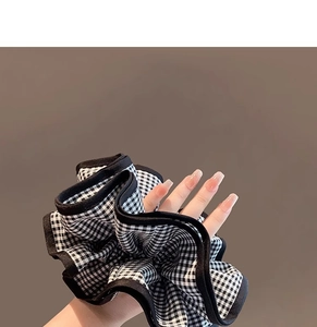 Détail d'un chouchou géant à carreaux noir et blanc porté au poignet avec texture tissu