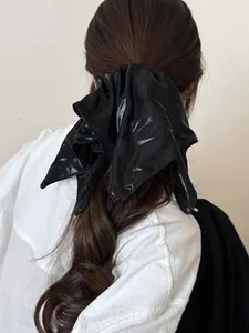 Glossy black faux leather scrunchie detail showing mirror-like shine and texture