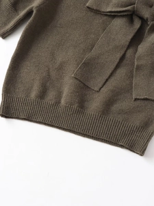 Gros plan du haut en maille vert olive montrant la texture fine et le grand nœud