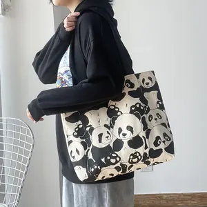 Close-up of large canvas tote bag featuring cute panda patterns and wide black straps