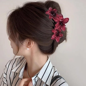 Detail view of a burgundy floral claw clip styled on dark brown hair in a half-up ponytail