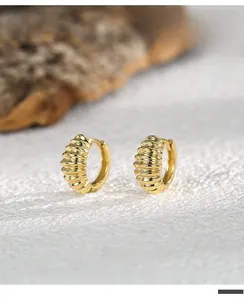 Detailed close-up of gold-plated croissant hoop earrings with ribbed texture design