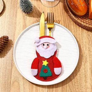 Close-up of Santa Claus themed cutlery holder with gold fork and knife on white plate