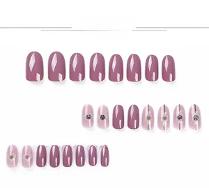 Detail view of pink and mauve press-on nails featuring floral patterns and small rhinestones