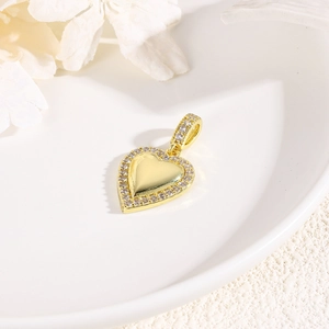 Detailed view of a gold heart pendant with zircon inlay on a white ceramic plate