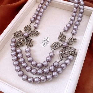 Close-up of triple-strand lavender pearl necklace with vintage rhinestone flower detail