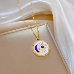 Evil eye and blue moon gold necklace with rhinestones on beige jewelry tray