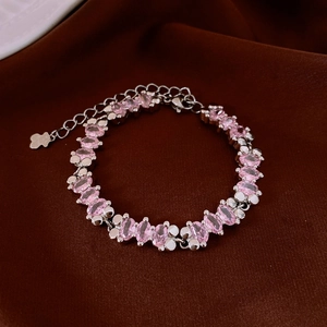 Detail view of pink oval zircon bracelet with silver chain on dark velvet surface
