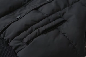 Dettaglio del gilet trapuntato nero con tasca laterale, bottoni metallici e orlo