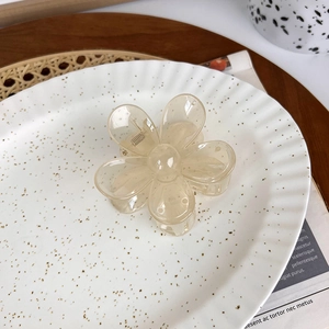Detail of a translucent champagne flower hair claw clip on a decorative white plate