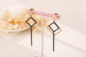 Detail of rose gold and black geometric earrings with long vertical drop pendant