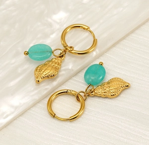 Close-up of gold shell hoop earrings with turquoise stones on wave background