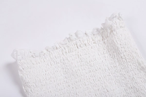 Détail rapproché du tissu élastique blanc froncé avec bordure en dentelle délicate