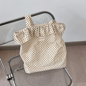 Detailed close-up of cream canvas tote bag with black polka dots and ruffle edge trim