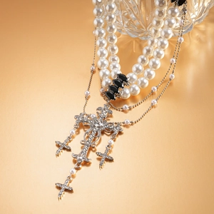 Detail of layered pearl sweater chain featuring crystal-encrusted crosses and black gems