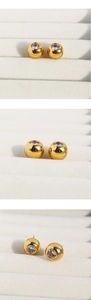 Detailed views of gold spherical stud earrings with clear round cubic zirconia setting