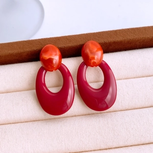 Detail of vintage acrylic oval earrings with orange marble stud and dark red hoop