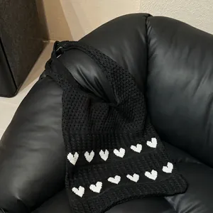 Black knitted tote bag with white heart patterns and striped texture shoulder strap