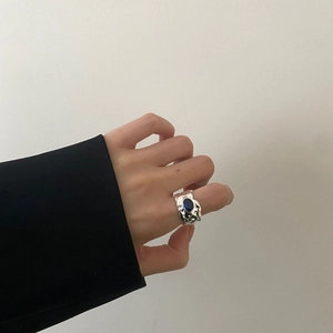 Detail of silver lava ring with blue gemstone worn on finger against grey backdrop