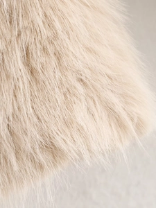 Close-up detail of soft faux fur fabric texture on a cream beige fashion jacket
