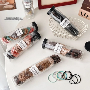 Macro detail of assorted elastic hair ties in a transparent storage tube with labeling