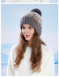 Outdoor close-up of a warm knit winter beanie with fur pom-pom and leather patch