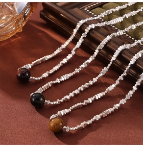 Macro detail of beaded stainless steel necklaces with tiger eye stone pendants on velvet