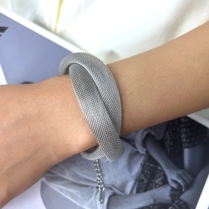 Detailed close-up of a silver mesh multi-layered steel bracelet with extension chain