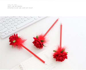 Three creative red rose ballpoint pens with feathers on a white desk with keyboard