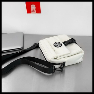 Detailed shot of white canvas messenger bag with black buckle on metal desk setting