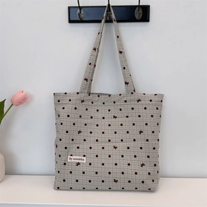 Vue détaillée du sac cabas en toile à pois avec motifs de nœuds rouges et étiquette logo