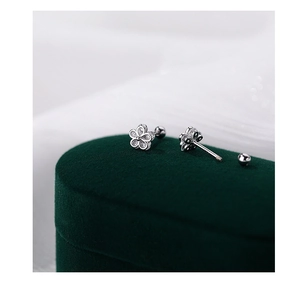 Macro shot of silver flower earrings with screw back on a green velvet box