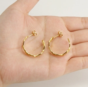 Macro detail of gold 18k stainless steel earrings with hammer texture in hand