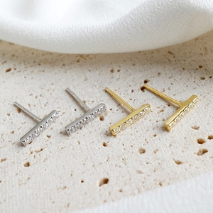 Close-up of minimalist bar stud earrings with row of zircons in gold and silver finish