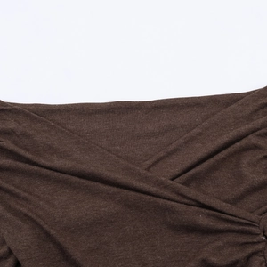 Dettaglio ravvicinato del tessuto in maglia marrone scuro con eleganti pieghe incrociate