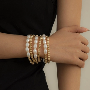 Elegant five-piece set of white pearl and gold bead bracelets on a model wrist