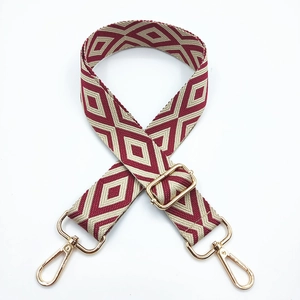 Close-up of embroidered geometric diamond bag strap with light gold metal buckles