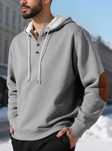 Détails des coudières marron et boutons en bois sur un sweat à capuche gris polaire