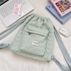 Quilted heart-patterned plaid drawstring backpack on desk with laptop and books