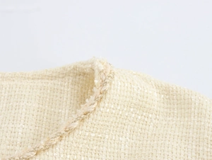 Détail du tissu en tweed beige avec bordure tressée sur cet ensemble élégant deux pièces
