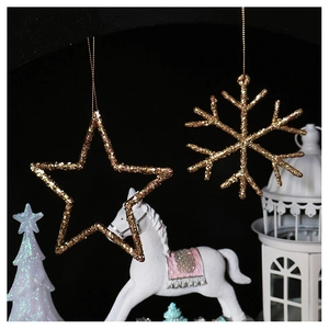 Close-up of golden glitter star and snowflake Christmas ornaments on a dark backdrop